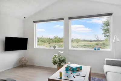 a living room with a couch and two windows at BL1377-Blokhus-Valmuemarken-37 in Blokhus