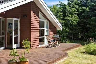 a wooden deck with a chair and a table on it at BL1727-Pandrup-Lunekrogen-16 in Pandrup