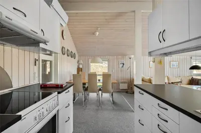 a kitchen with white cabinets and a dining room at BL244-Blokhus-Moreavej-17 in Blokhus