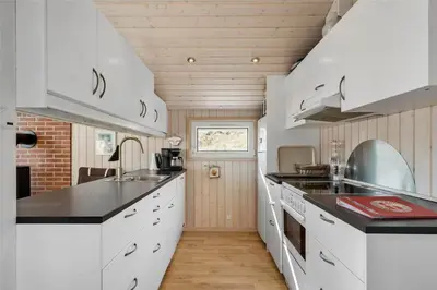 a kitchen with white cabinets and black counter tops at BL244-Blokhus-Moreavej-17 in Blokhus