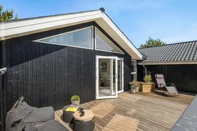 a black house with a deck with a sliding glass door at BL1346-Blokhus-Septimusvej-19 in Blokhus
