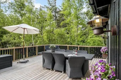 a deck with a table and chairs and an umbrella at BL958-Blokhus-Havorns-Alle-14 in Blokhus