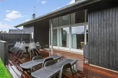 a deck with chairs and tables on a house at BL698-Blokhus-Kr-Thomsensvej-3 in Blokhus