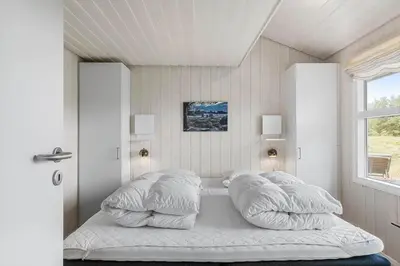 a bedroom with a bed with pillows and a window at BL1243-Saltum-Kvansletten-22 in Saltum