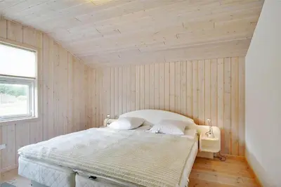 a bedroom with a bed in a room with wooden walls at BL1299-Saltum-Bondagervej-44 in Saltum
