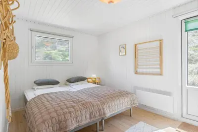 a bedroom with a bed and two windows at BL1668-Blokhus-Skraavejen-4 in Blokhus