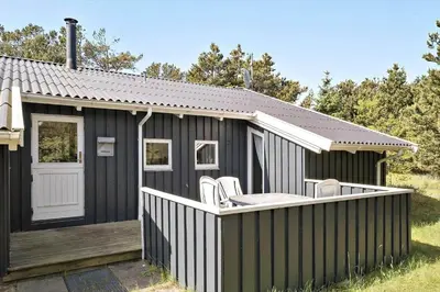 a black shed with two white chairs on a deck at BL164-Saltum-Lyngsletten-7 in Saltum