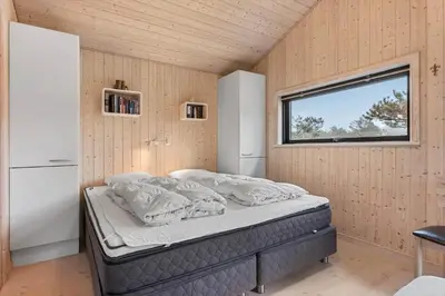 a bedroom with a bed in a room with a window at BL842-Blokhus-Laerkevej-29 in Blokhus