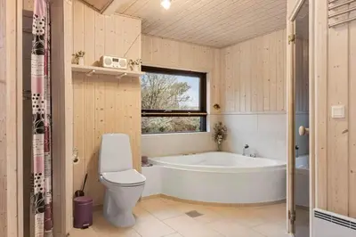 a bathroom with a tub and a toilet and a sink at BL842-Blokhus-Laerkevej-29 in Blokhus