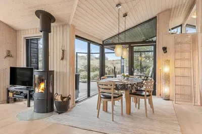 a dining room with a table and a fireplace at BL842-Blokhus-Laerkevej-29 in Blokhus