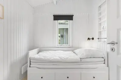 a white bedroom with a bed and a window at BL1448-Pandrup-Hunetorp-Klitvej-215 in Pandrup