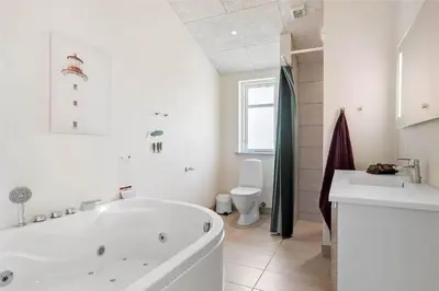 a white bathroom with a tub and a toilet at BL1704-Blokhus-Pirupvejen-66 in Blokhus