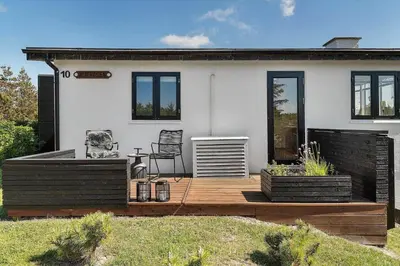 a house with a wooden deck in front of it at BL1550-Blokhus-Poppelvej-10 in Blokhus