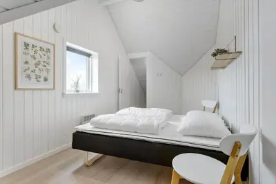 a white room with a bed and a chair at BL1567-Blokhus-Klitvejen-6 in Blokhus