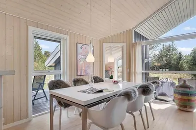 a dining room with a table and chairs and windows at BL1262-Pandrup-Hunetorp-Klitvej-5 in Pandrup