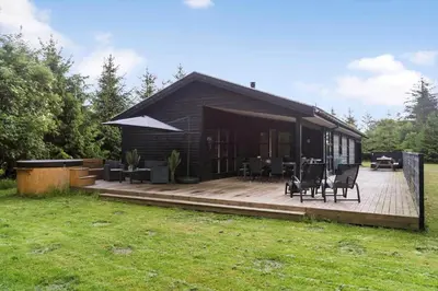 a house with a wooden deck with chairs and tables at BL191-Blokhus-Bloksbjerg-13 in Blokhus