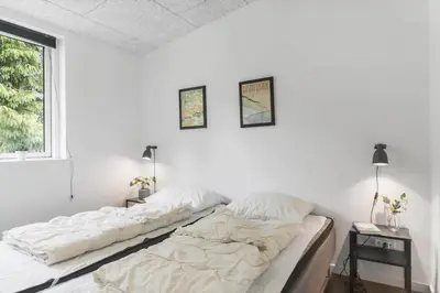 a bed in a white room with two pictures on the wall at BL191-Blokhus-Bloksbjerg-13 in Blokhus