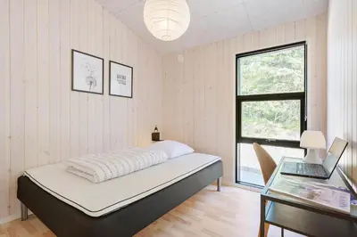 a bedroom with a bed and a desk and a window at BL1565-Blokhus-Plantagevej-2-A in Blokhus