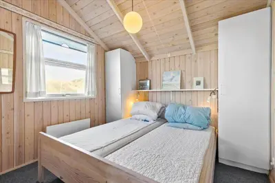 a bedroom with a bed in a room with a window at BL1747-Blokhus-Norresundbyvej-22 in Blokhus