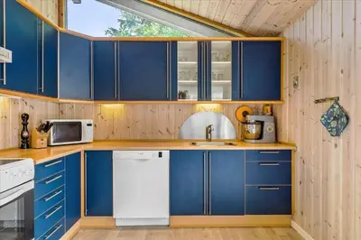 a kitchen with blue cabinets and a white dishwasher at BL1417-Blokhus-Frederiksensvej-16 in Blokhus