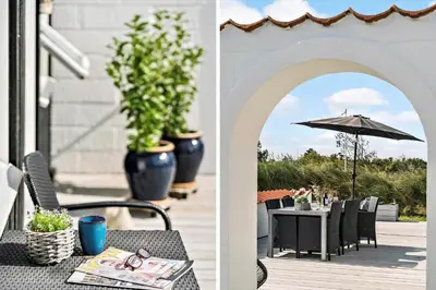 a patio with an umbrella and a table with chairs at BL1549-Blokhus-Bakkevaenget-11 in Blokhus