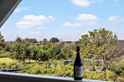 a bottle of wine sitting on a window with two wine glasses at BL1549-Blokhus-Bakkevaenget-11 in Blokhus