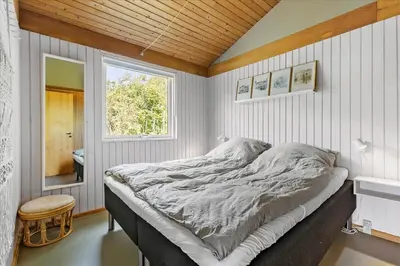 a bedroom with a bed in a room with a window at BL1728-Blokhus-Kaeruldvej-7 in Blokhus