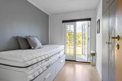 a bed in a room with a window and a door at BL1136-Blokhus-Graevlingevej-6 in Blokhus
