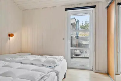 a room with four white beds and a window at BL239-Blokhus-Klitgaardsvej-21 in Blokhus