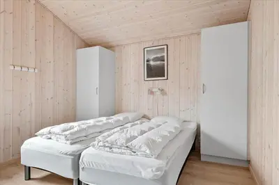 a room with four white beds in it at BL239-Blokhus-Klitgaardsvej-21 in Blokhus