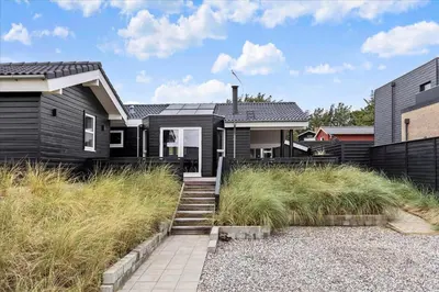 a black house with a pathway in front of it at BL239-Blokhus-Klitgaardsvej-21 in Blokhus