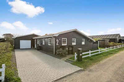 a brown house with a white fence and a driveway at BL856-Blokhus-Soren-Tjenersvej-2 in Blokhus