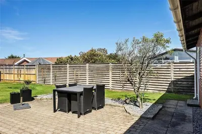 a patio with a black table and a fence at BL141-Blokhus-Vigen-12 in Blokhus