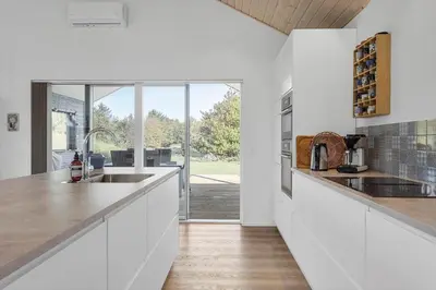 a kitchen with white cabinets and a large window at BL1317-Blokhus-Frederiksensvej-5 in Blokhus