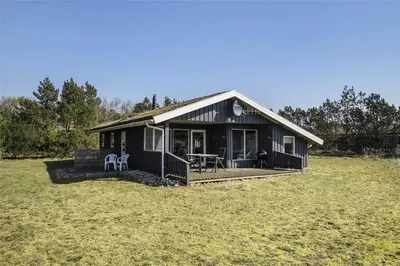 a small black house with a deck in a field at BL1051-Pandrup-Rodhus-Skolevej-11 in Pandrup