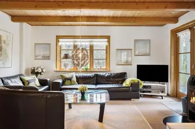 a living room with a leather couch and a tv at BL1553-Pandrup-Lunekrogen-9 in Pandrup