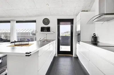 a kitchen with white counters and a clock on the wall at BL400-Blokhus-Sdr-Strandvej-9-B in Blokhus