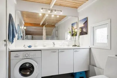 a white bathroom with a washing machine and a sink at BL1329-Blokhus-Pirupshvarrevej-67 in Blokhus