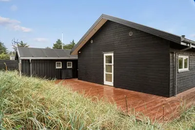 a black house with a deck in front of it at BL1403-Blokhus-Sorensensvej-7 in Blokhus