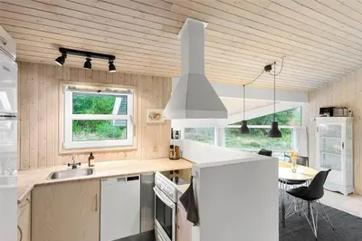 a kitchen with a white refrigerator and a table at BL1259-Blokhus-Bag-Hojen-83 in Blokhus