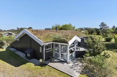 a house with a grass roof with a deck at BL256-Blokhus-Skytten-35 in Blokhus