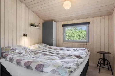a bedroom with a bed in a room with a window at BL256-Blokhus-Skytten-35 in Blokhus