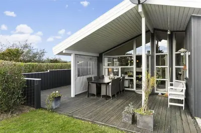 a house with a wooden deck with a table at BL256-Blokhus-Skytten-35 in Blokhus