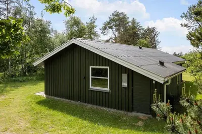 a small black building with a window in a field at BL433-Blokhus-Raappenmark-8 in Blokhus