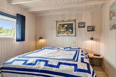 a bedroom with a bed with a blue and white comforter at BL173-Blokhus-Bloksbjerg-88 in Blokhus