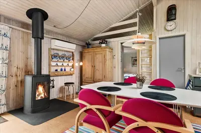 a room with a table and chairs and a fireplace at BL173-Blokhus-Bloksbjerg-88 in Blokhus