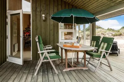 a table and chairs with an umbrella on a porch at BL1202-Saltum-Revlingevej-6 in Saltum