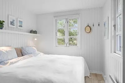 a white bedroom with a bed and a window at BL1280-Blokhus-Bloksbjerg-50 in Blokhus
