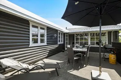 a patio with a table and chairs and an umbrella at BL1284-Blokhus-Tyttebaervej-4 in Blokhus