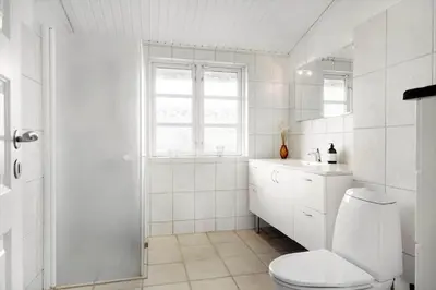 a white bathroom with a toilet and a sink at BL1284-Blokhus-Tyttebaervej-4 in Blokhus